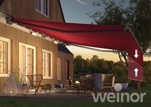 Moderne Terrassenüberdachung mit roter Markise und LED-Beleuchtung an einem Holzhaus.